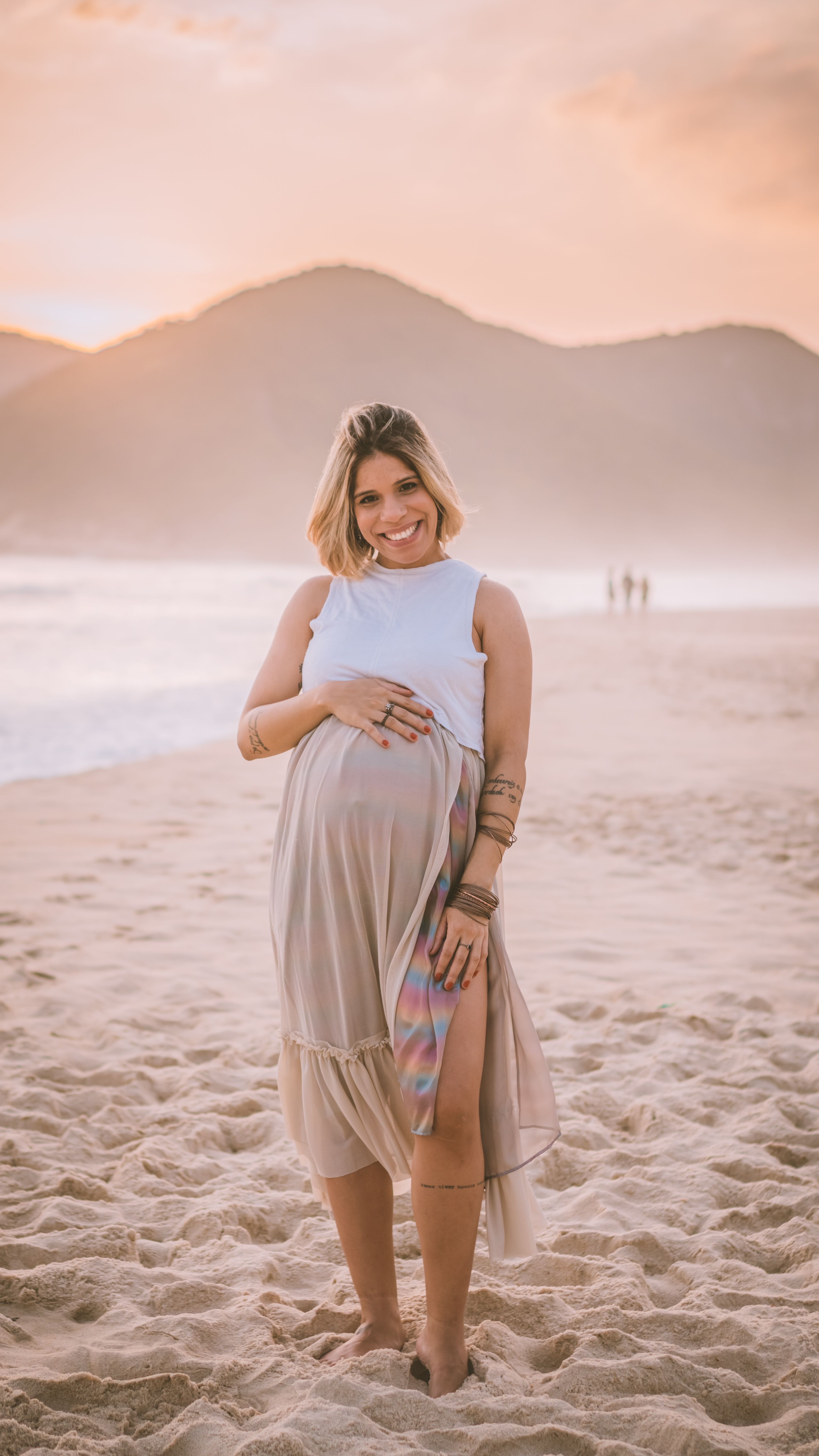 Mãe grávida sorrindo, com as mãos na barriga